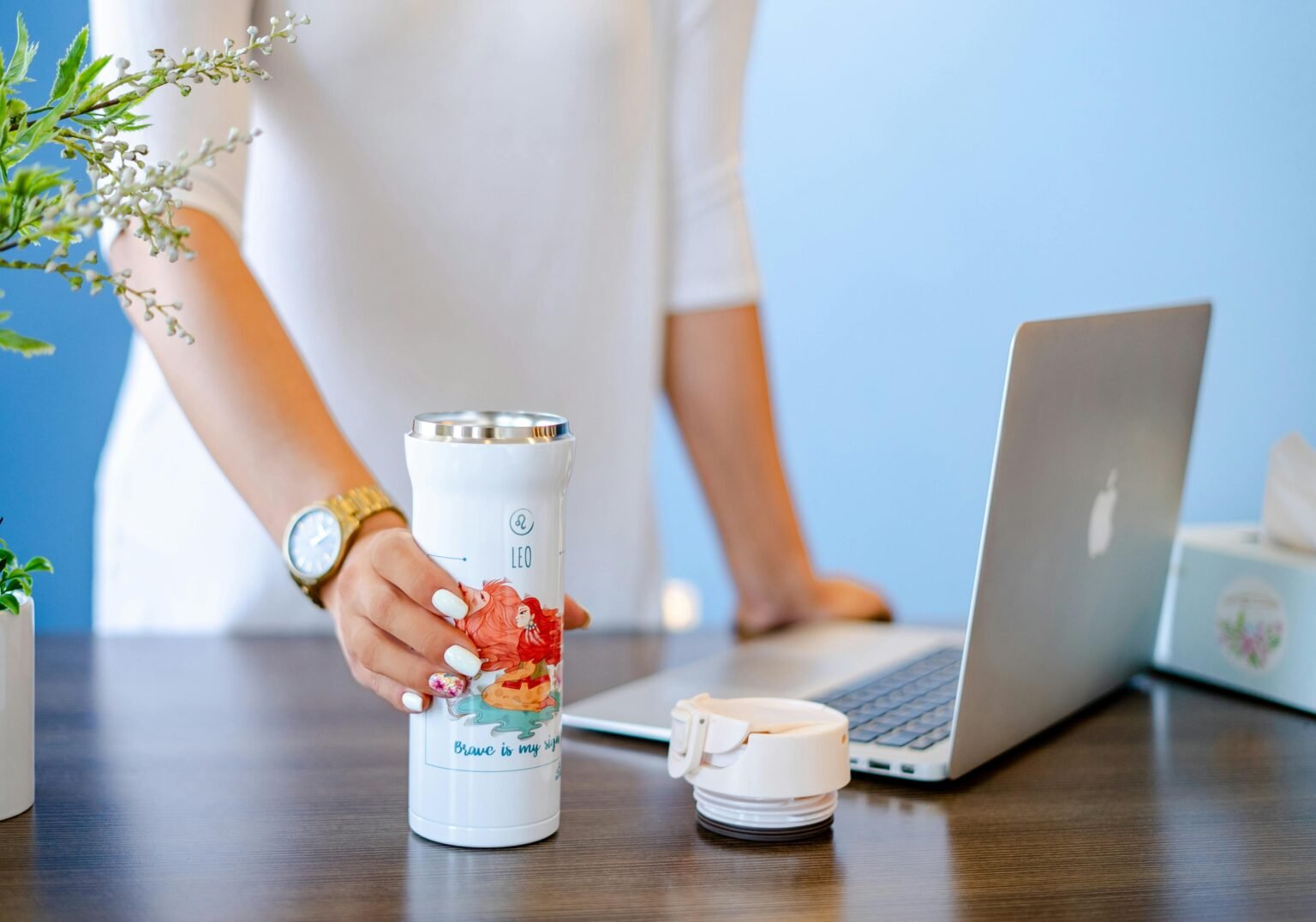 A person happily holding a stylish tumbler filled with iced coffee outdoors